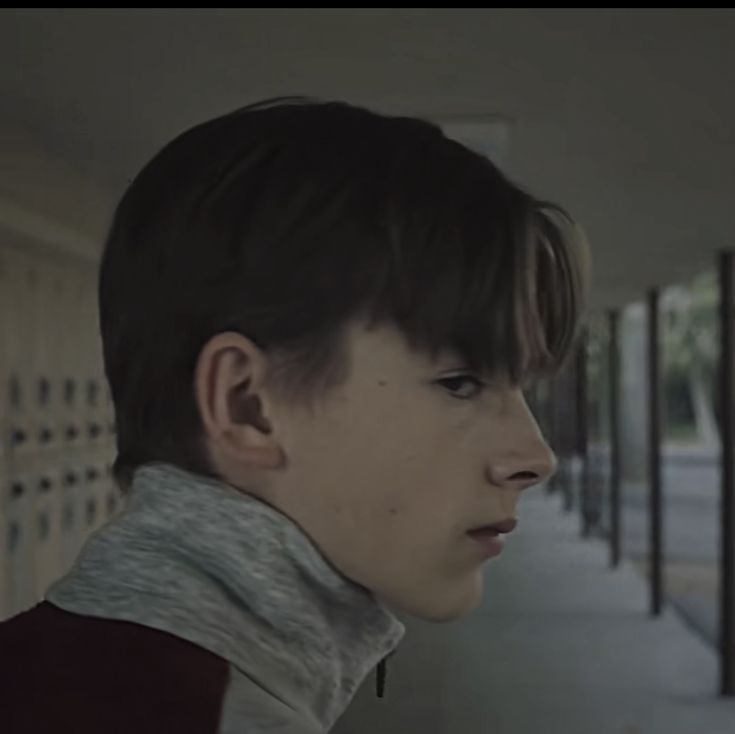 a young man standing in front of a building with his head tilted to the side