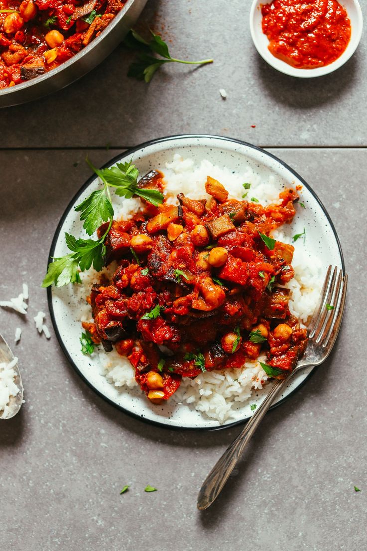 a plate with rice, beans and meat on it next to two bowls of sauce