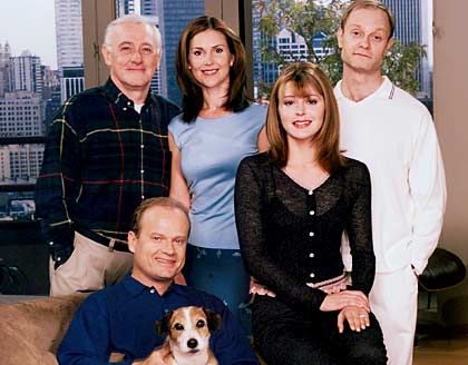 a group of people posing for a photo in front of a window with a dog