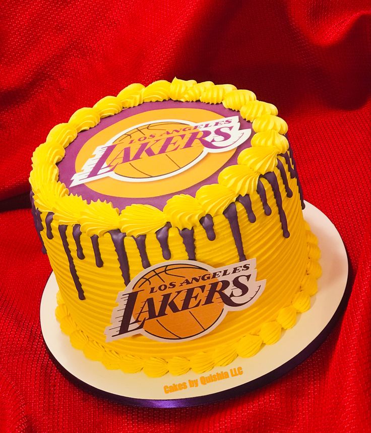 a birthday cake with the los angeles lakers logo on it is sitting on a red cloth