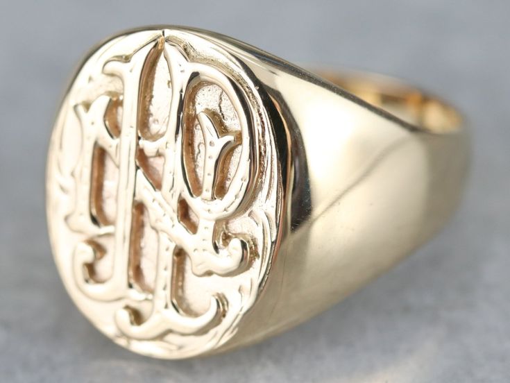 a gold signet ring with the letter g on it's center and two initials in the middle