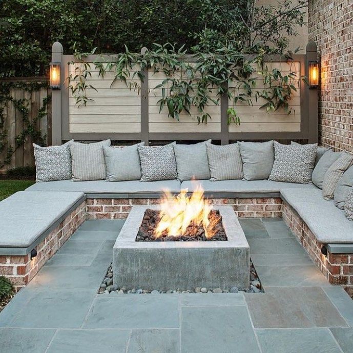 a fire pit in the middle of a patio with lots of pillows on top of it