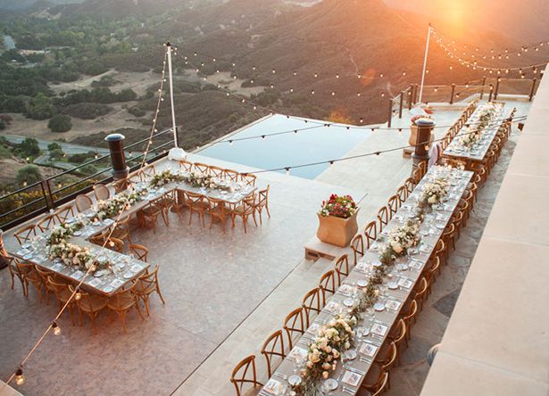 an outdoor dining table set up on top of a building with mountains in the background