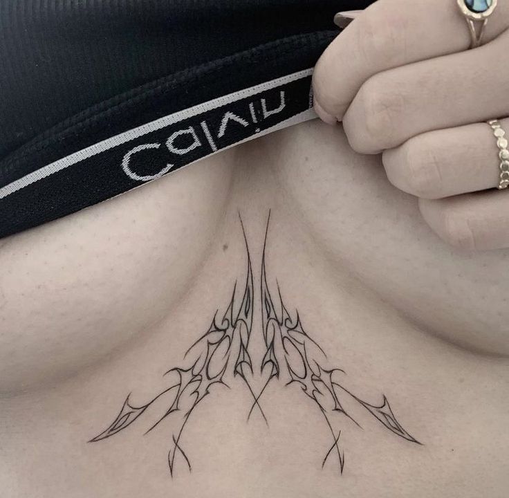 a close up of a person's stomach with tattoos on her chest and hand