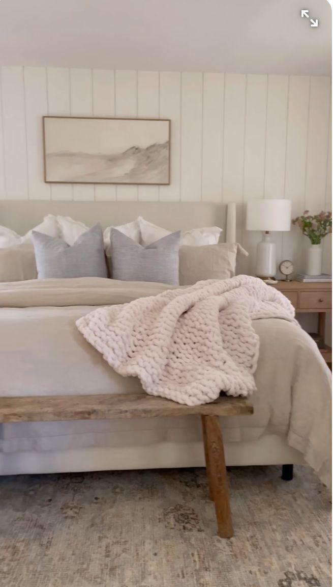 a bed with white sheets and pillows on top of it next to a wooden bench