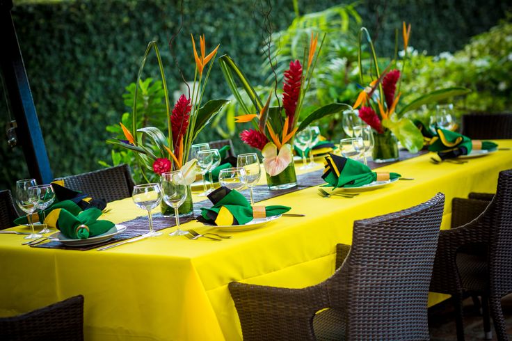 the table is set with yellow cloths and green napkins, which are decorated with flowers