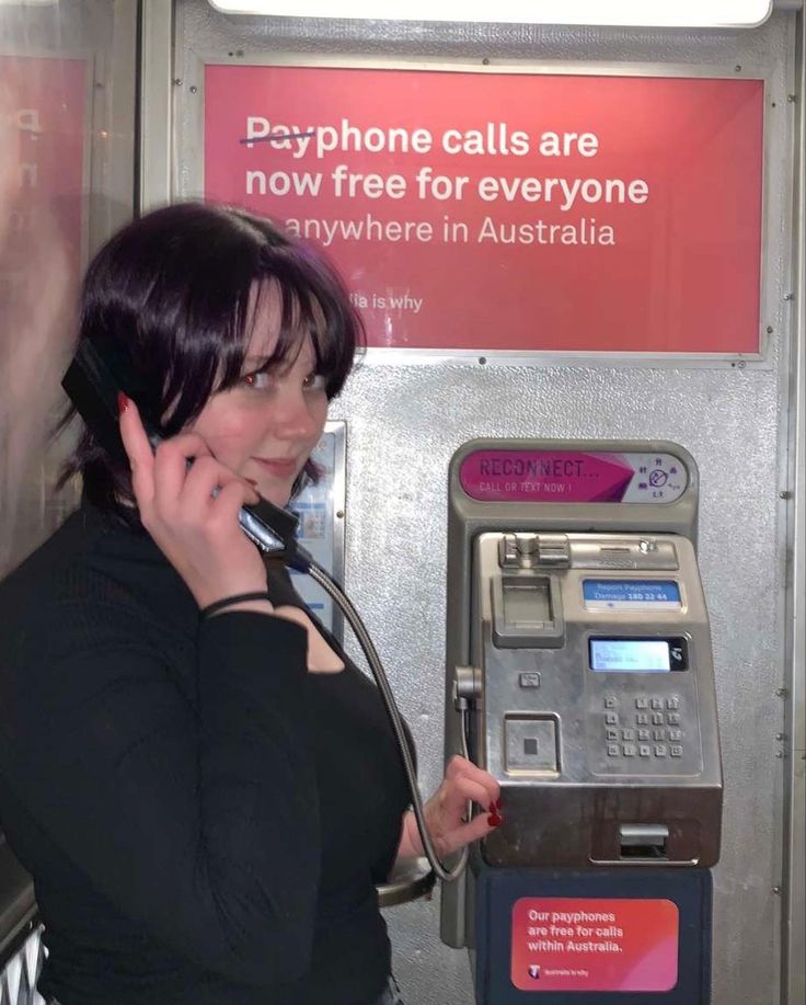 a woman is talking on the phone while using an atm machine