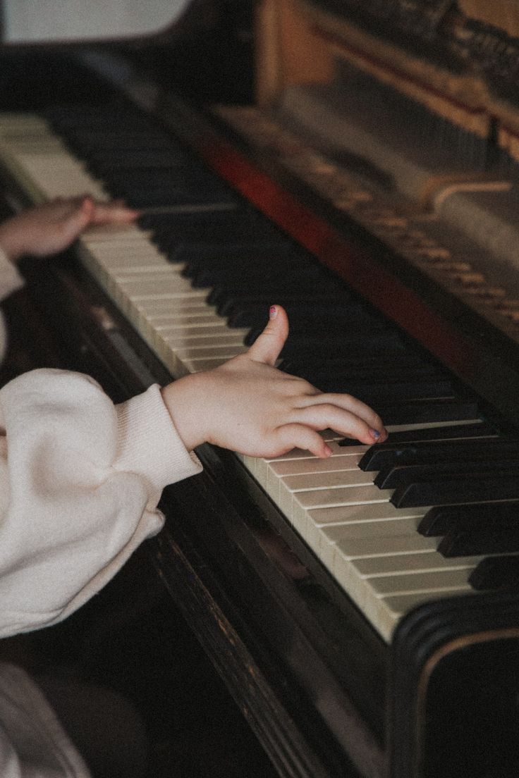 a young child is playing the piano with her hand on it's keys,