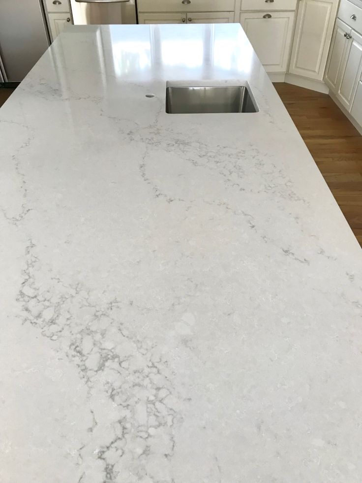 a kitchen with white cabinets and marble countertops in the middle of the island area