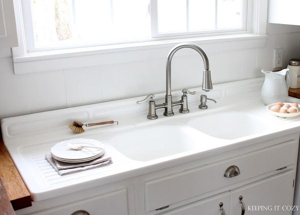 a kitchen sink with two faucets and plates on the counter next to it