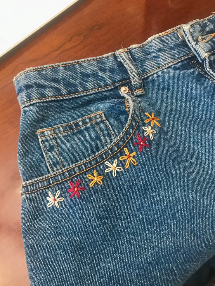 a pair of jeans with embroidered flowers on them