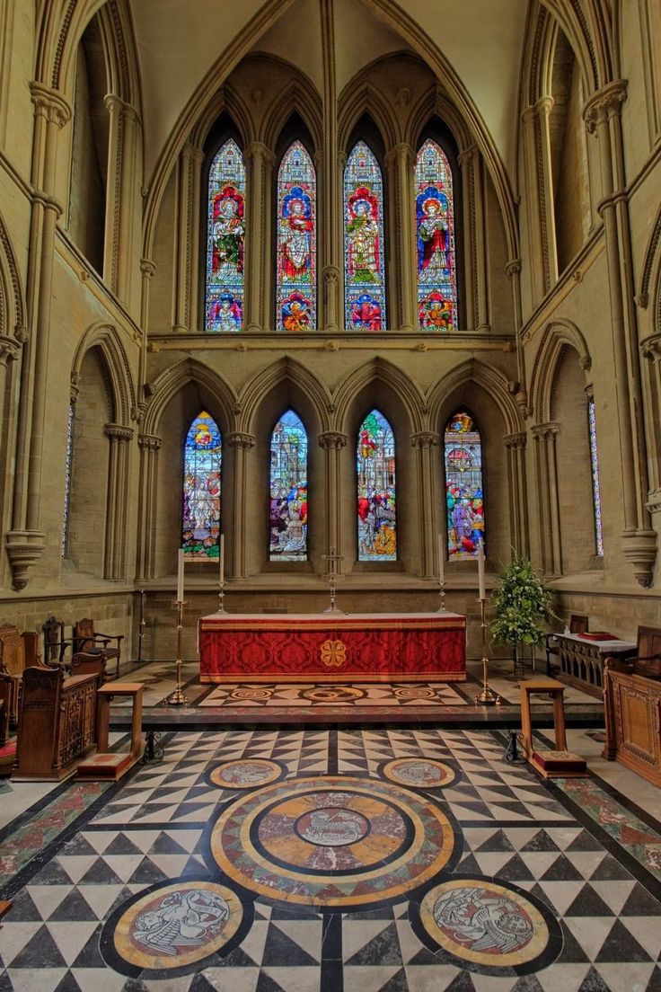 the inside of a church with stained glass windows and pews on either side of the alter