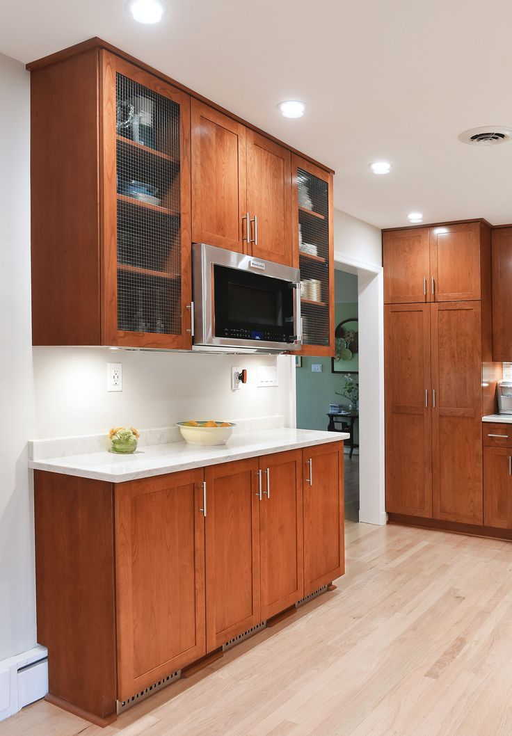 a kitchen with wooden cabinets and white counter tops, along with a microwave on the wall