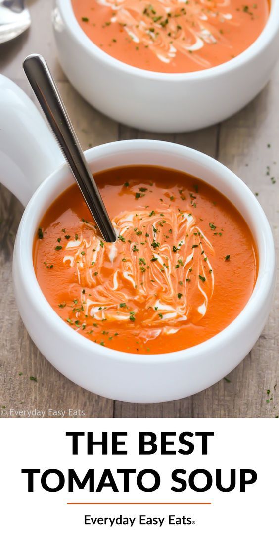 two white bowls filled with tomato soup on top of a wooden table