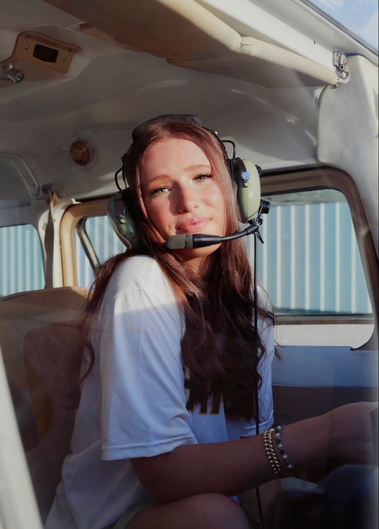 a woman sitting in the cockpit of an airplane with headphones attached to her ears