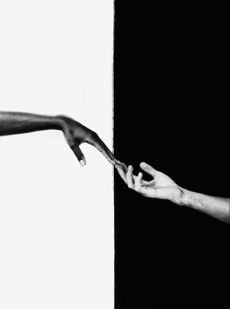 two people reaching out their hands to touch each other's hand in black and white