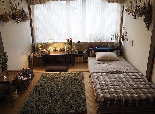 a bed sitting in the middle of a living room next to a dresser and window