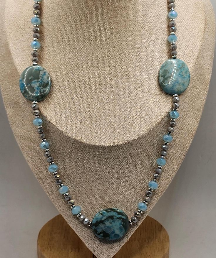 Elevate your style with this stunning handcrafted necklace featuring a beautiful combination of turquoise stones, crystals and silver accents. The centerpiece includes three large , polished turquoise stones, each showcasing unique patterns and vibrant hue. Interspersed between the turquoise are delicate light blue crystal beads and shimmering silver spacer beads, adding touch of elegance and contrast. The necklace is designed to lay gracefully around the neck, making it a perfect accessory for Adjustable Turquoise Stone Necklace, Adjustable Turquoise Stone Necklaces, Silver Turquoise Chrysocolla Necklace With Natural Stones, Silver Turquoise Necklace With Chrysocolla Stones, Blue Chrysocolla Necklace With Stones, Elegant Turquoise Agate Beaded Necklaces, Artisan Turquoise Beaded Necklaces With Stones, Elegant Turquoise Crystal Necklaces With Natural Stones, Turquoise Chrysocolla Stone Necklaces