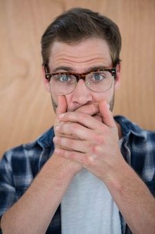 a man with glasses is covering his mouth