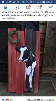 a wooden sign with a cow painted on it and a wreath hanging from the side