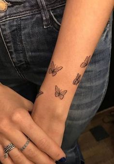 a woman's arm with butterfly tattoos on her left wrist and the other hand