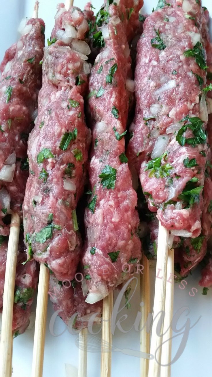 several skewers of meat with herbs on them