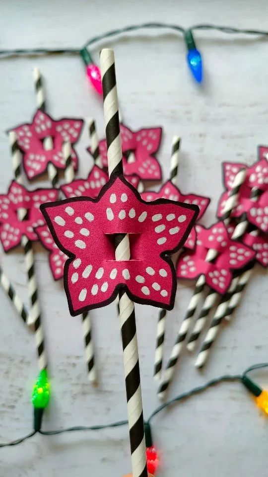 pink and black striped straws with bows on them sitting next to candy canes