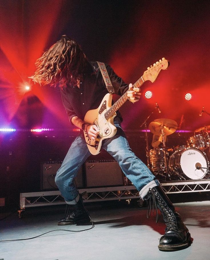 a man with long hair playing guitar on stage