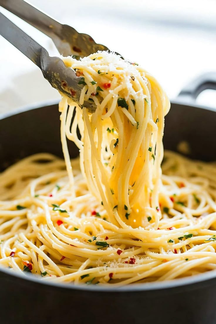 a fork full of spaghetti being lifted from a skillet