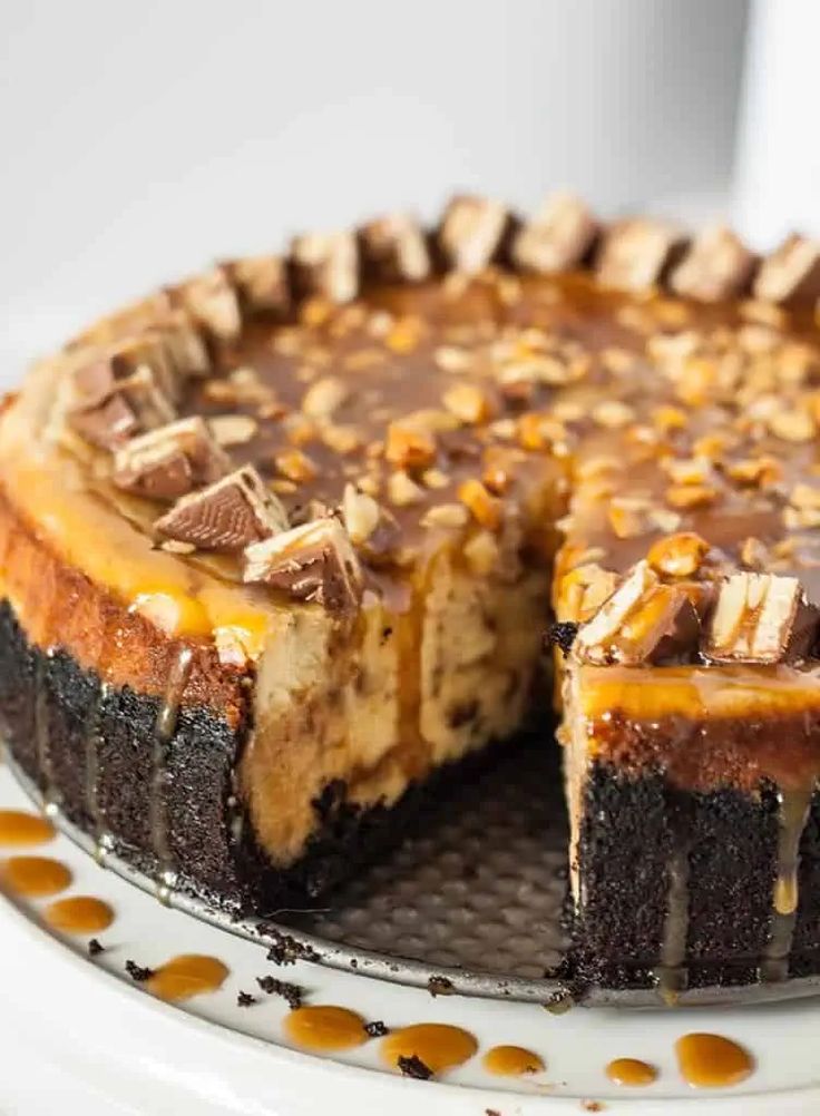 a chocolate cheesecake with peanut butter topping on a white cake plate, ready to be eaten