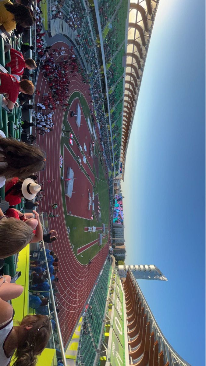 people are standing in the stands at an indoor track and field event, looking up into the sky