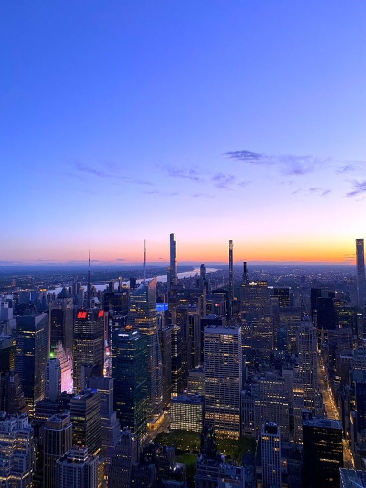 the city skyline is lit up at night with bright lights and skyscrapers in the background