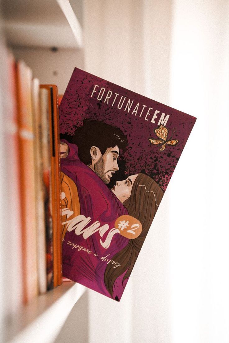 a book with an image of a man and woman on it hanging from a bookshelf