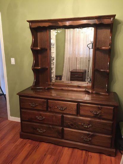 an old dresser with a mirror on it in a room that is painted green and has hardwood floors