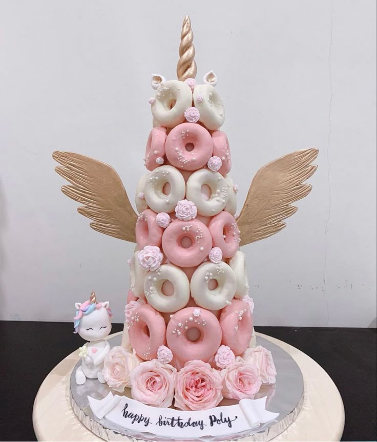 a birthday cake decorated with donuts, roses and an angel's horn on top