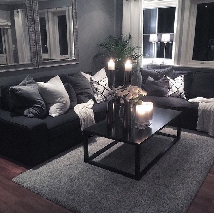 a living room filled with furniture and candles on top of a coffee table in front of a window