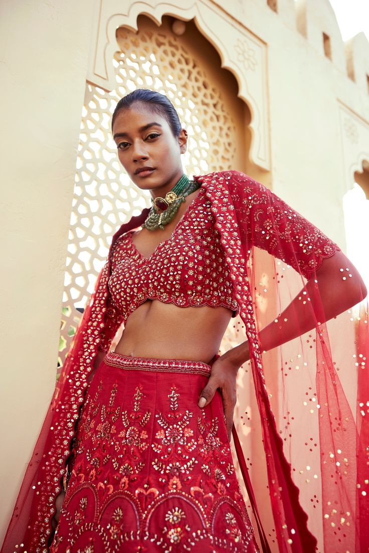 Red raw silk floral embroidered lehenga with thread work and sequence detailing paired with scallop edge v neck elbow sleeve heavily embroidered blouse and matching tulle dupatta with embroidered border and all over badla .From Chamee and Palak's The Romantics collection.DELIVERY TIMEPlease allow 8-12 weeks for your outfit to arrive.FABRIC DETAILSRaw Silk and Net Professional cleaning only. Festive V-neck Lehenga With Dupatta, Navratri Sharara With Zari Work And V-neck, Festive V-neck Sets With Resham Embroidery, Designer Bollywood Lehenga With V-neck, Bollywood Style V-neck Lehenga For Designer Wear, Chanderi V-neck Sets For Wedding, V-neck Resham Embroidered Sharara For Diwali, V-neck Chanderi Sets For Wedding, Bollywood Style V-neck Lehenga With Dupatta