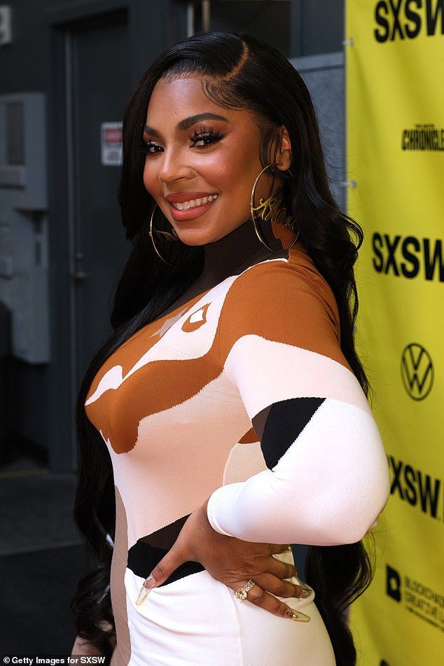 a woman in a white and brown dress posing for the camera with her hands on her hips