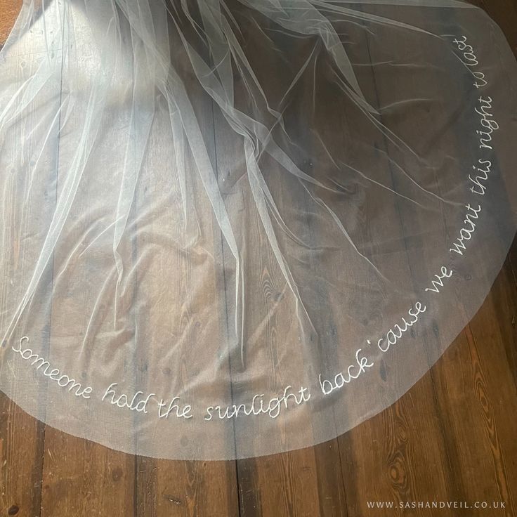 a bride's veil with words written on it is laying on the floor in front of her wedding dress