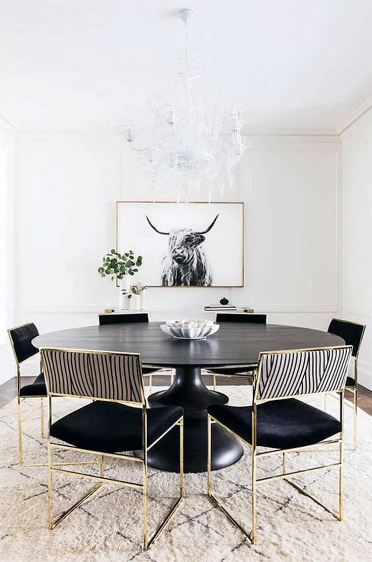 a dining room table with chairs and a chandelier hanging above it on the wall