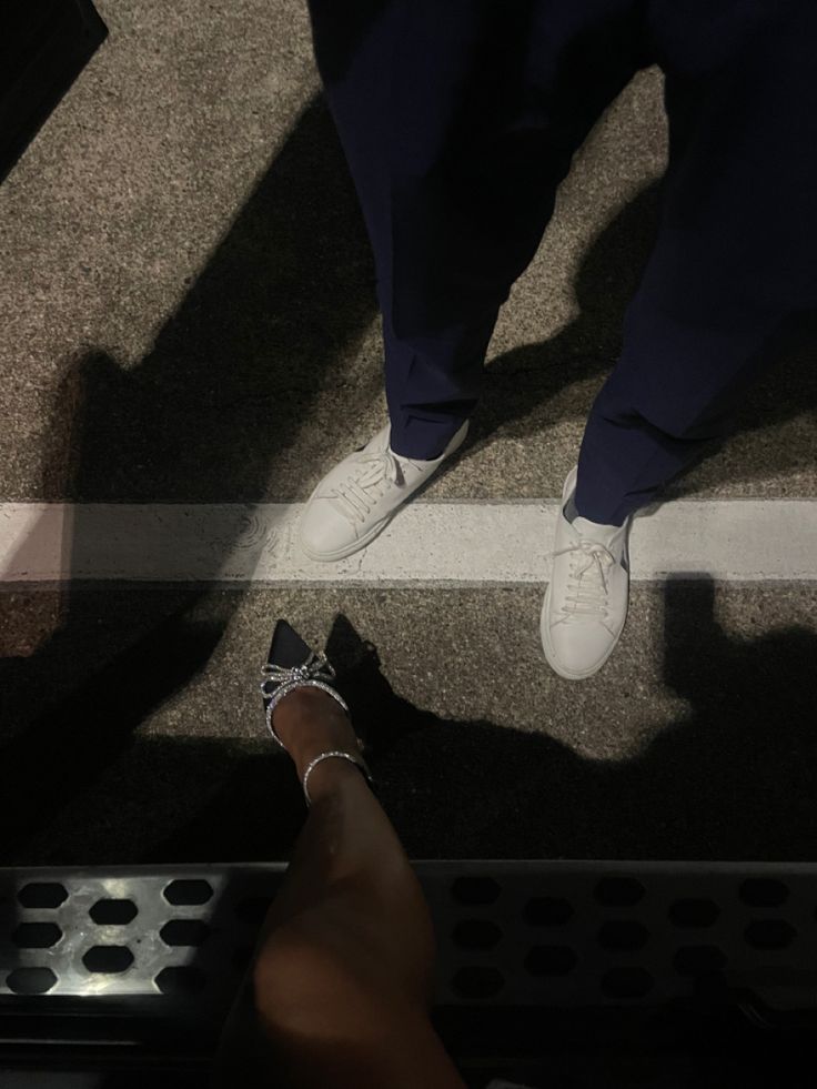 two people standing next to each other in front of a metal grate on the ground