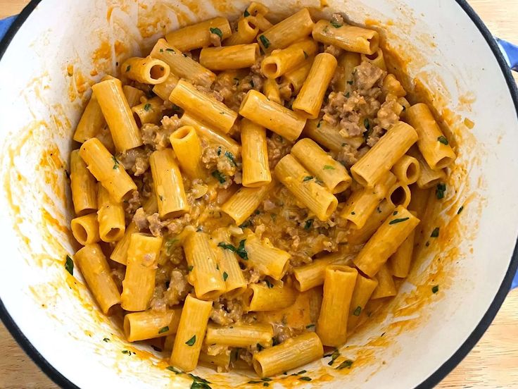 a pot filled with pasta and meat on top of a wooden table