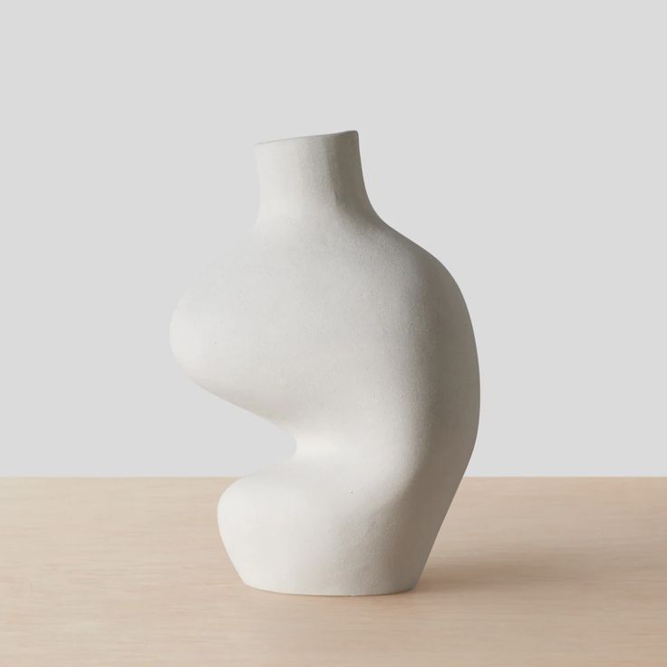 a white vase sitting on top of a wooden table