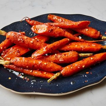 a blue plate topped with sliced carrots covered in sauce