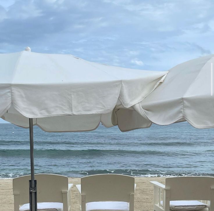 chairs and umbrellas are on the beach by the ocean