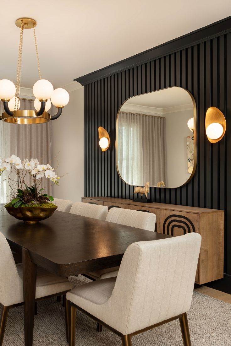 a dining room table with chairs and a large mirror on the wall above it that is next to a window