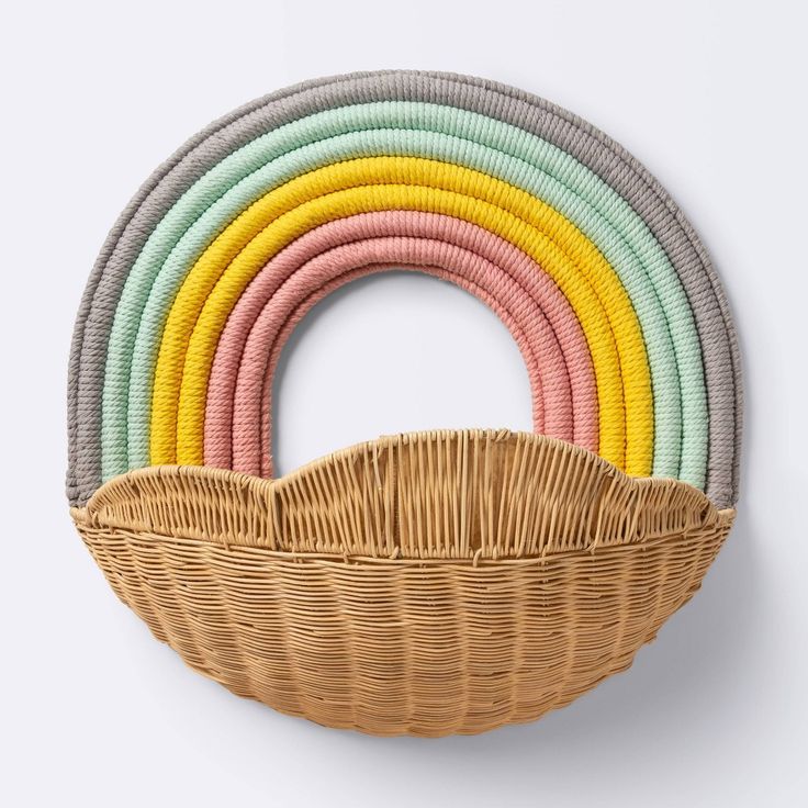 a wicker basket with multicolored rings hanging from it's side on a white wall