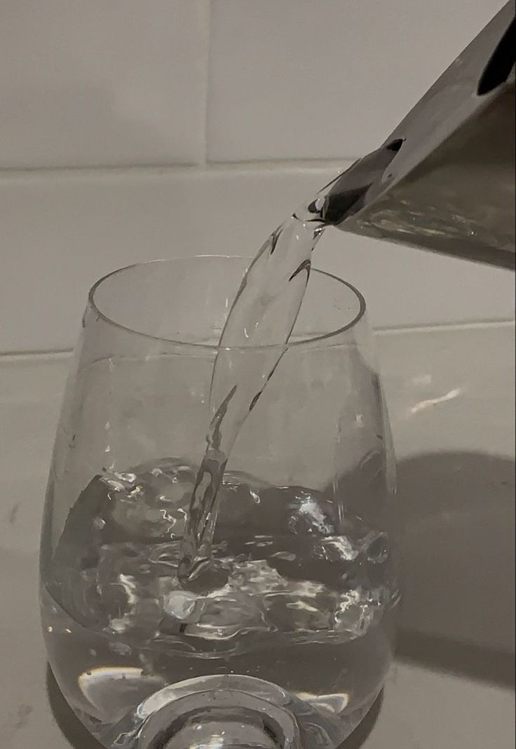 water being poured into a glass on top of a counter