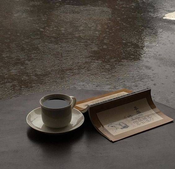 a cup of coffee sitting on top of a table next to an open envelope and umbrella