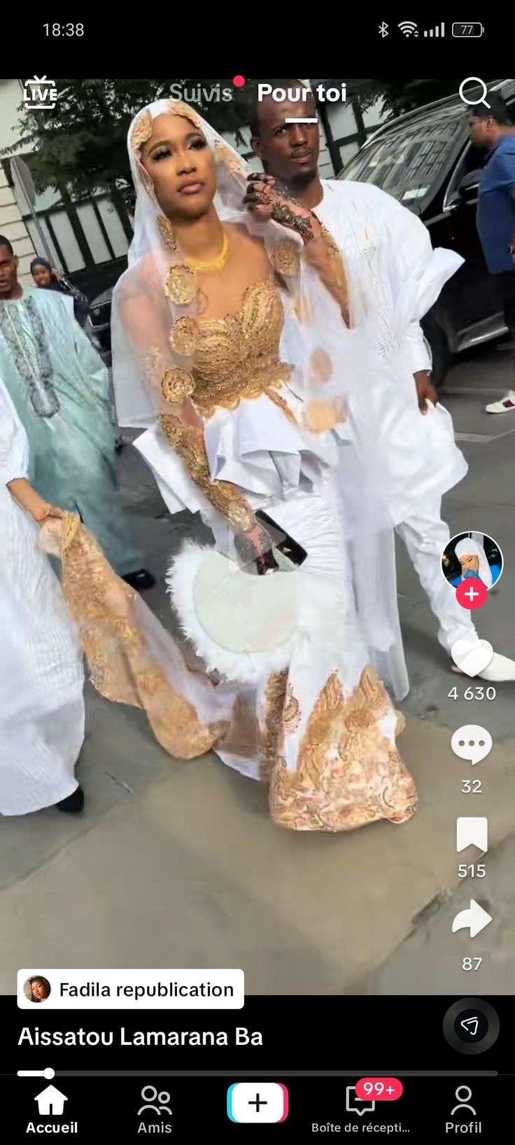 two people dressed in white and gold dancing on the street with other people behind them